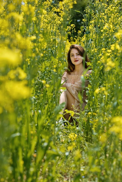 Mujer joven rodeada de flores de canola Campo de flor de primavera