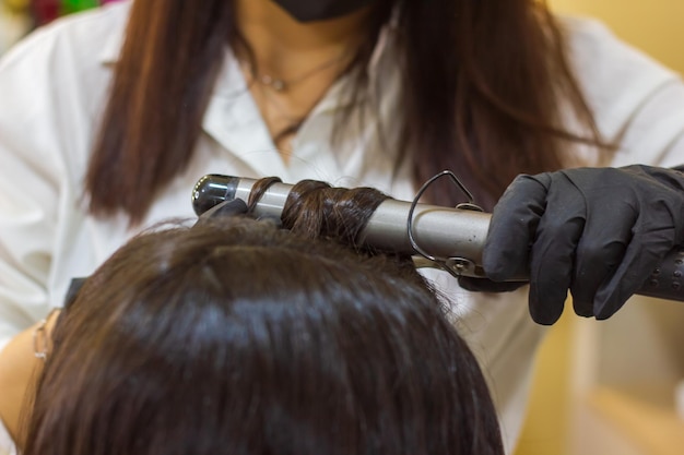 mujer joven con rodillos de cabello mujer joven en el salón de peluquería el peluquero