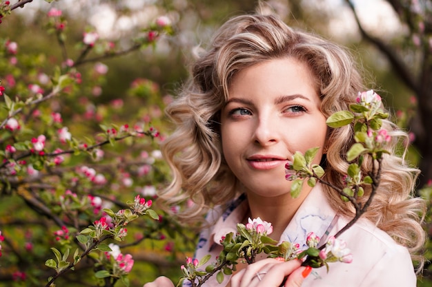 Mujer joven romántica en el jardín de primavera entre flor de manzano. Mujer hermosa, primavera feliz