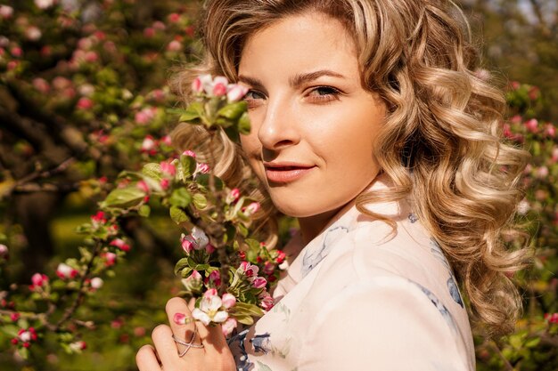 Mujer joven romántica en el jardín de primavera entre flor de manzano. Mujer hermosa, primavera feliz