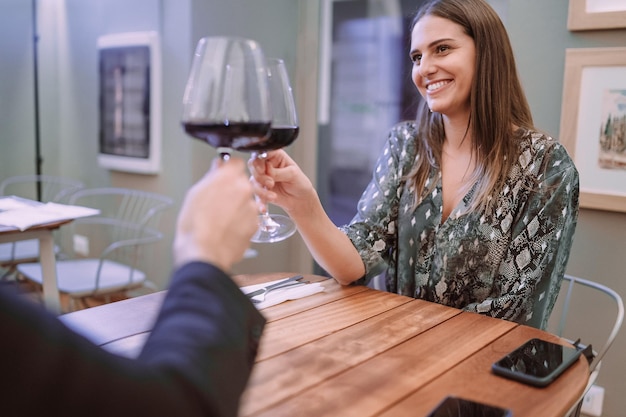 Mujer joven con un romántico brindis con vino de celebración Pareja tintineo de copas de vino en un restaurante