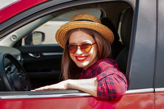 Mujer joven en ropa casual sonriendo mientras conduce un automóvil