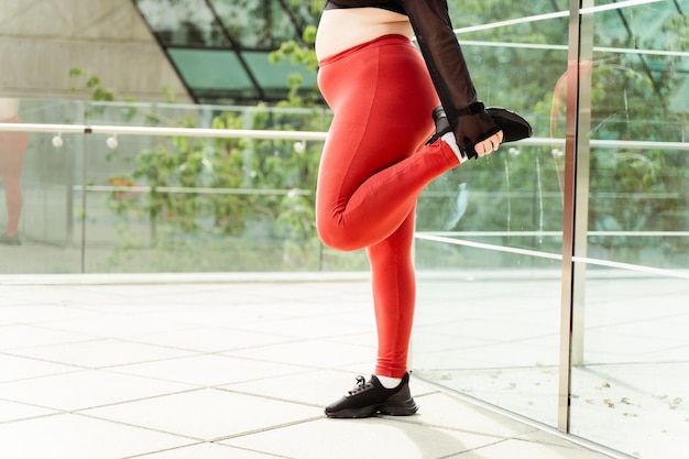 Mujer joven en ropa deportiva estirándose en la ciudad Entrenamiento de motivación de modelo de talla plus