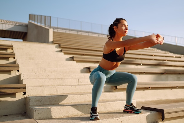 Mujer joven en ropa deportiva haciendo ejercicios al aire libre en la mañana Mujer haciendo ejercicio de estiramiento