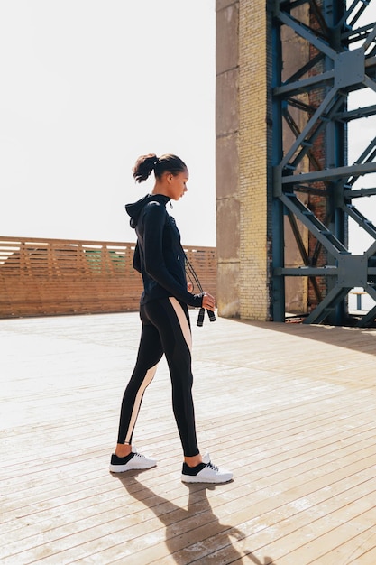 Mujer joven en ropa deportiva preparándose para entrenar con saltar la cuerda