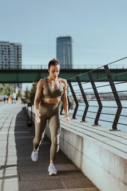 Mujer joven en ropa deportiva que se extiende en un paseo fluvial