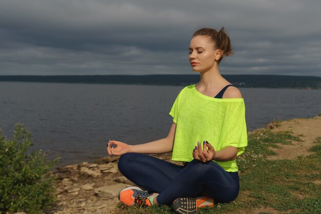 Mujer joven, en, ropa deportiva, sentado, en, orilla del río