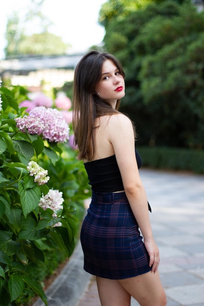 Mujer joven con ropa elegante posando en un parque paradisíaco