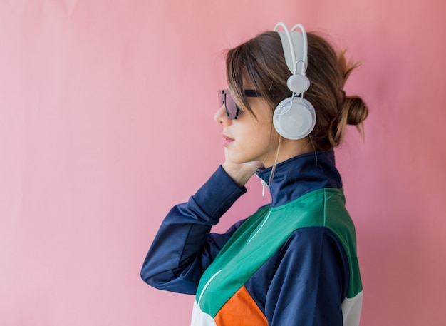 Mujer joven en ropa de estilo años 90 con auriculares en rosa