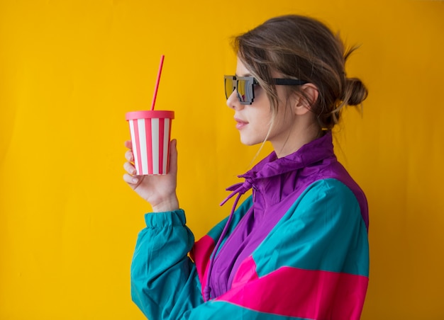 Mujer joven en ropa de estilo años 90 con taza