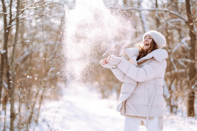 Mujer joven en ropa de estilo de invierno caminando en el parque nevado Vacaciones de moda de invierno