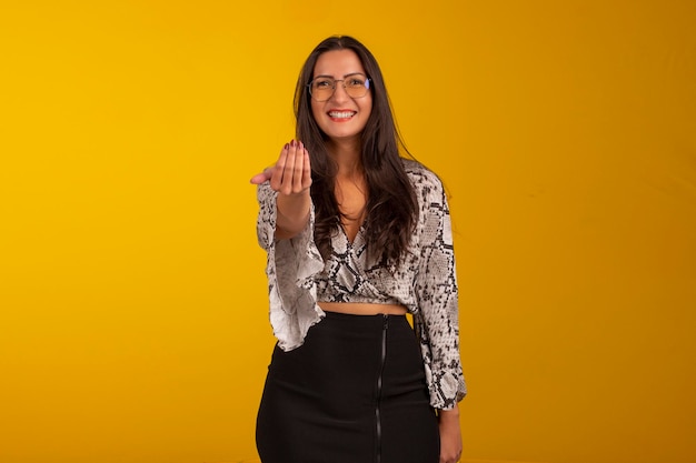 Mujer joven con ropa formal y anteojos en foto de estudio con fondo amarillo