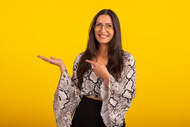 Mujer joven con ropa formal y anteojos en foto de estudio con fondo amarillo