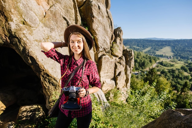 Mujer joven con ropa hipster con cámara fotográfica vintage viajando por las montañas rocosas