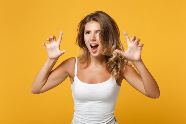 Mujer joven con ropa informal ligera posando aislada en un retrato de estudio de fondo naranja amarillo. Concepto de estilo de vida de las personas. Simulacros de espacio de copia. Gritando, gruñendo como un animal, haciendo gestos de garras de gato.