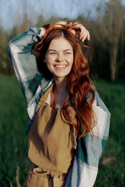 Una mujer joven con ropa de trabajo y un delantal al aire libre disfrutando de la puesta de sol y relajándose después de un duro día de trabajo