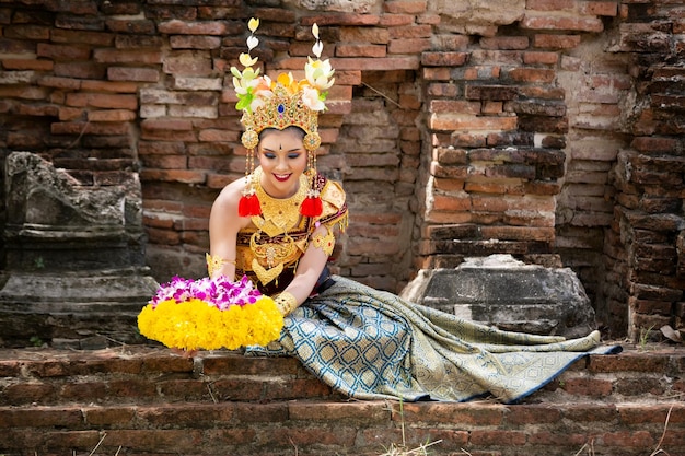 Foto mujer joven con ropa tradicional con flores sentada en el templo