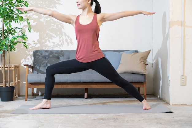 Mujer joven con ropa de yoga haciendo yoga en la habitación