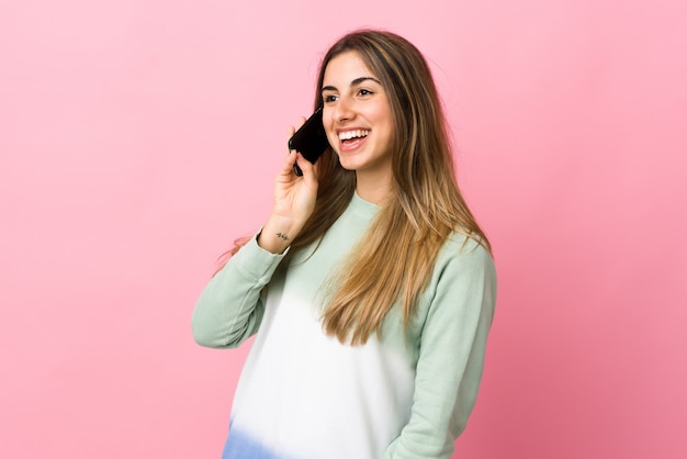 Mujer joven en rosa aislado manteniendo una conversación con el teléfono móvil