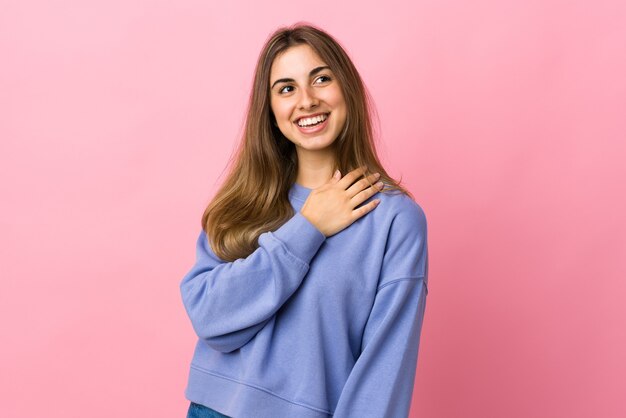 Mujer joven en rosa aislado mirando hacia arriba mientras sonríe