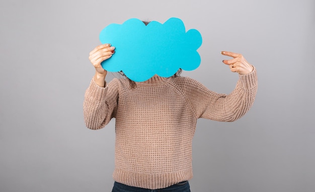 Mujer joven con el rostro cubierto con una nube azul sobre fondo gris