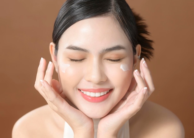 Una mujer joven con un rostro hermoso sostiene crema usando crema de su rostro concepto de cuidado de la piel de belleza
