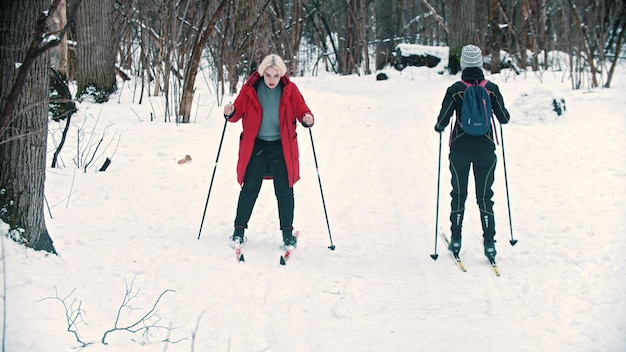 Una mujer joven y rubia caminando sobre esquí en el bosque