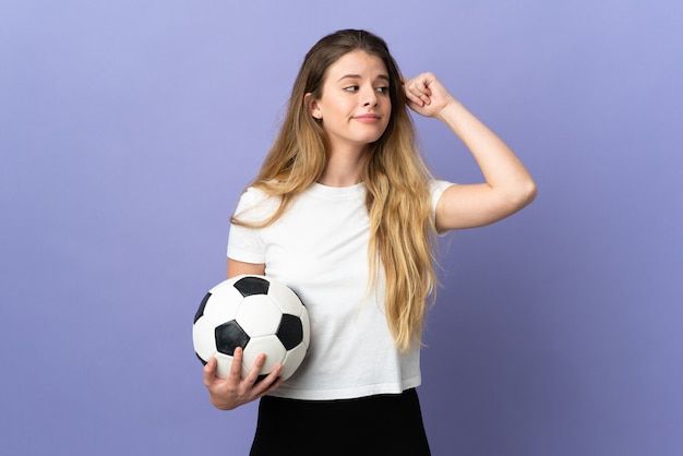 Mujer joven rubia jugador de fútbol aislada en el espacio púrpura que tiene dudas y pensamiento