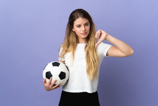 Mujer joven rubia jugador de fútbol aislada en la pared púrpura que muestra el pulgar hacia abajo con expresión negativa