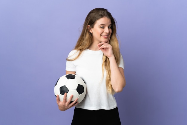 Mujer joven rubia jugador de fútbol posando aislada contra la pared en blanco