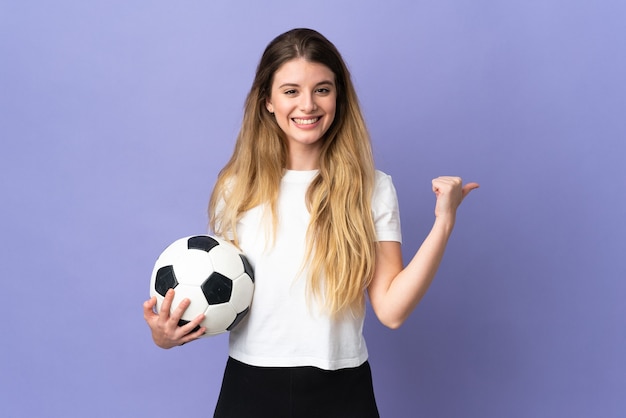 Mujer joven rubia jugador de fútbol posando aislada contra la pared en blanco