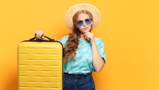 Mujer joven rubia con maleta amarilla. vacaciones o concepto de viaje