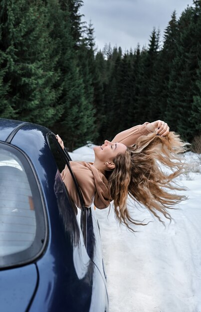 Mujer joven rubia con el pelo largo en el coche cogiendo el viento