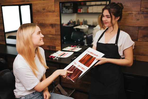 Mujer joven rubia sonriente que señala en el color del pelo de la paleta