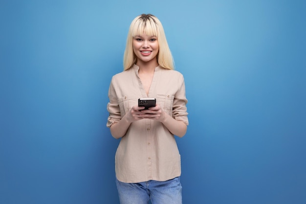 Mujer joven rubia sorprendida envía un mensaje usando un teléfono inteligente