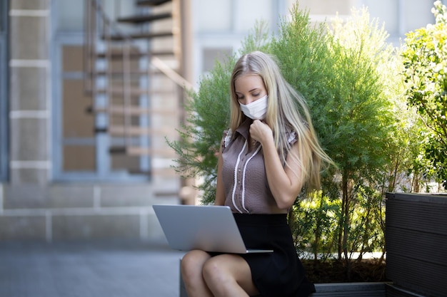 Mujer joven rubia usando una computadora portátil en un café y usando tecnología de Internet en línea