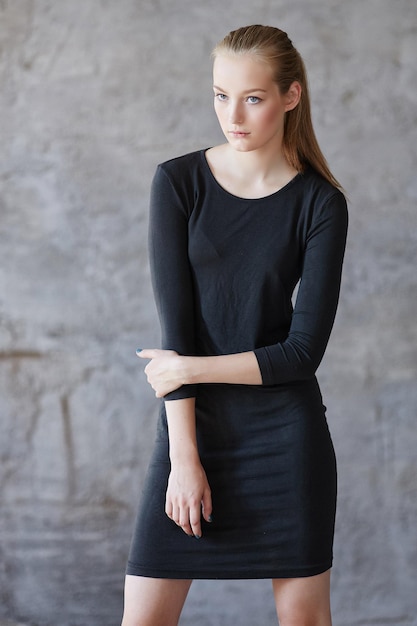 Mujer joven rubia con un vestido negro.