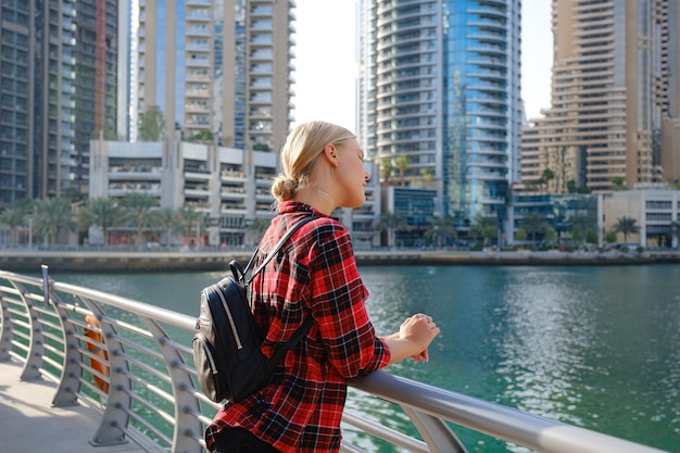 Mujer joven rubia viajes caminando por la calle al aire libre en la ciudad de Dubai. Marina de Dubai en Emiratos Árabes Unidos. Destino de verano de los Emiratos Árabes Unidos.