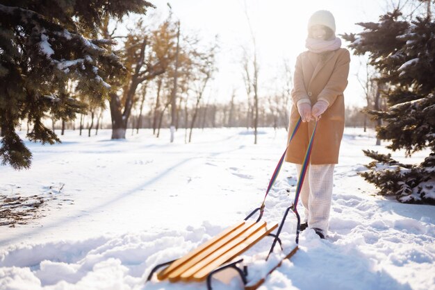 Mujer joven rueda en un trineo en el bosque nevado de invierno Naturaleza vacaciones descanso concepto de viaje