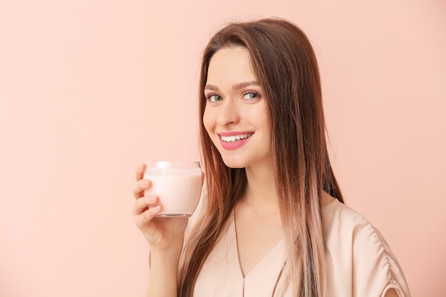 Mujer joven con sabroso yogur en la superficie de color