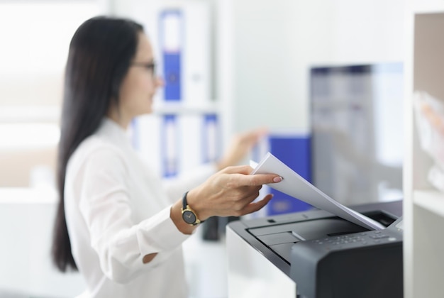 Mujer joven sacando papel del primer plano de la impresora