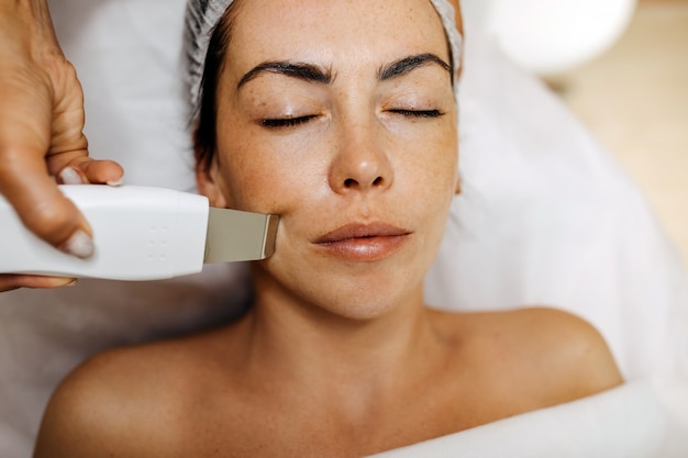 Mujer joven en un salón de belleza con un masaje facial