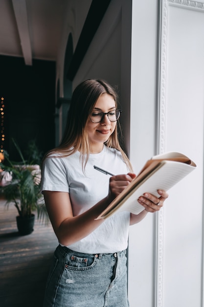 Mujer joven en salón de negocios, tomando notas en un bloc de notas.