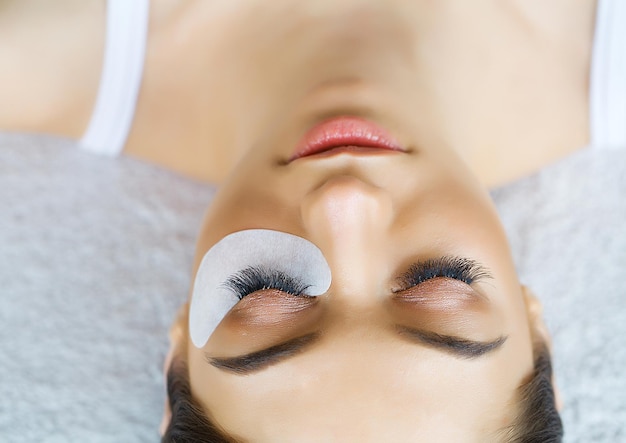 Mujer joven en el salón de spa haciendo el procedimiento de extensión de pestañas.