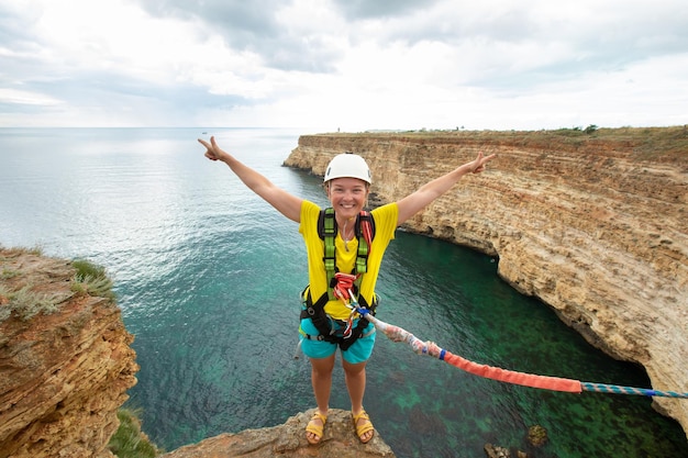 Mujer joven salta desde el acantilado con una cuerda Ropejumping