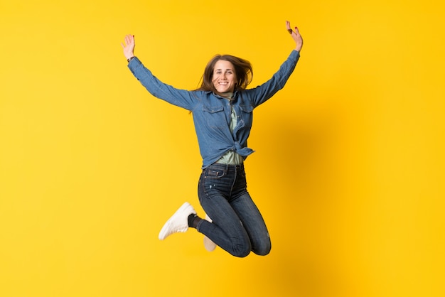 Mujer joven saltando sobre amarillo