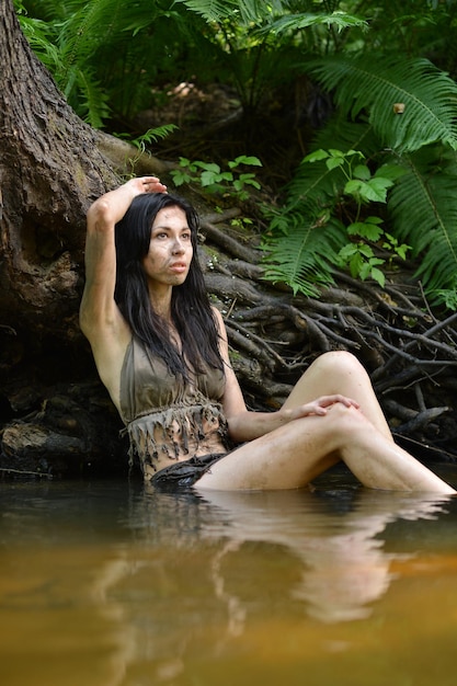 Mujer joven salvaje en ropa negra posando en el río