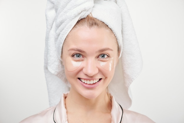 Mujer joven sana con una gran sonrisa disfrutando de un refrescante procedimiento debajo de los ojos de forma aislada