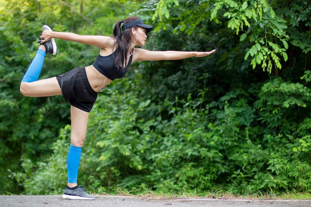 Mujer joven sana que practica yoga antes de correr el entrenamiento. Mujer haciendo deportes al aire libre.