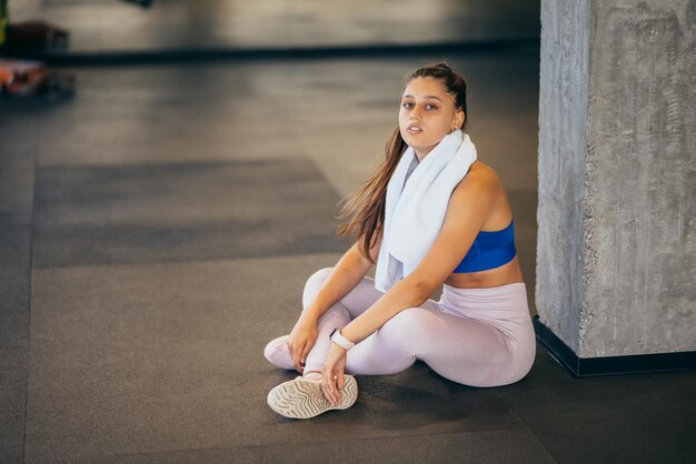 Mujer joven sana sentada relajada después de entrenar en el gimnasio